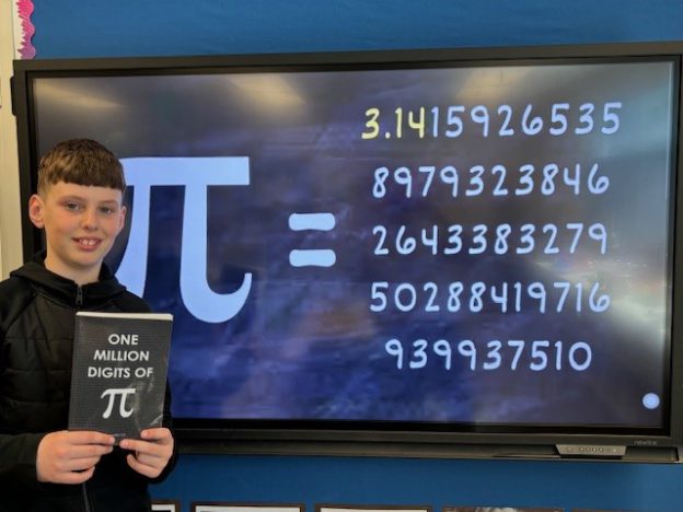 young boy holding book titled "One Hundred Digits of Pi" in front of screen displaying many digits of Pi.